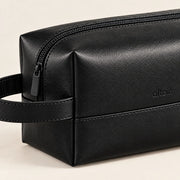 Detail of the black ALTAIR wash bag's leather-look finish and zip